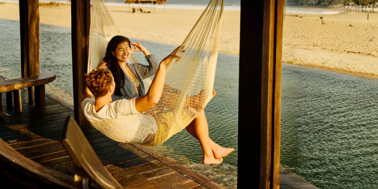 Couple swinging in over water hammock